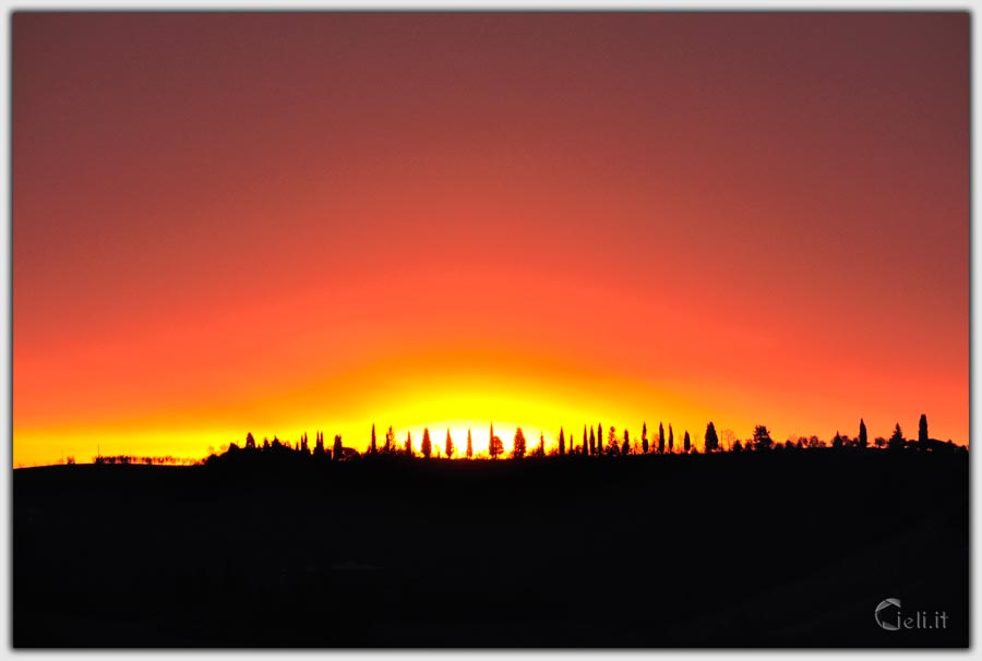 mattino presto con cielo senza nuvole, sole che tocca la cima delle colline e cipressi che brillano mattino presto con cielo senza nuvole, sole che tocca la cima delle colline e cipressi che brillano