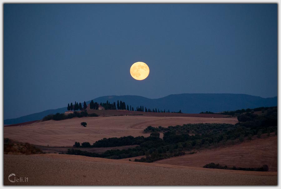 Serata con luna sospesa sopra la collina, pace e ombre scure nell'aria notturna
