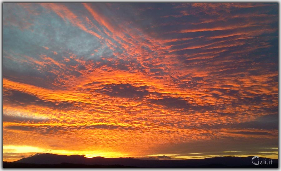 Tramonto con cielo ardente e nuvole colorate. Vitalità e bellezza in un momento incalcolabile.